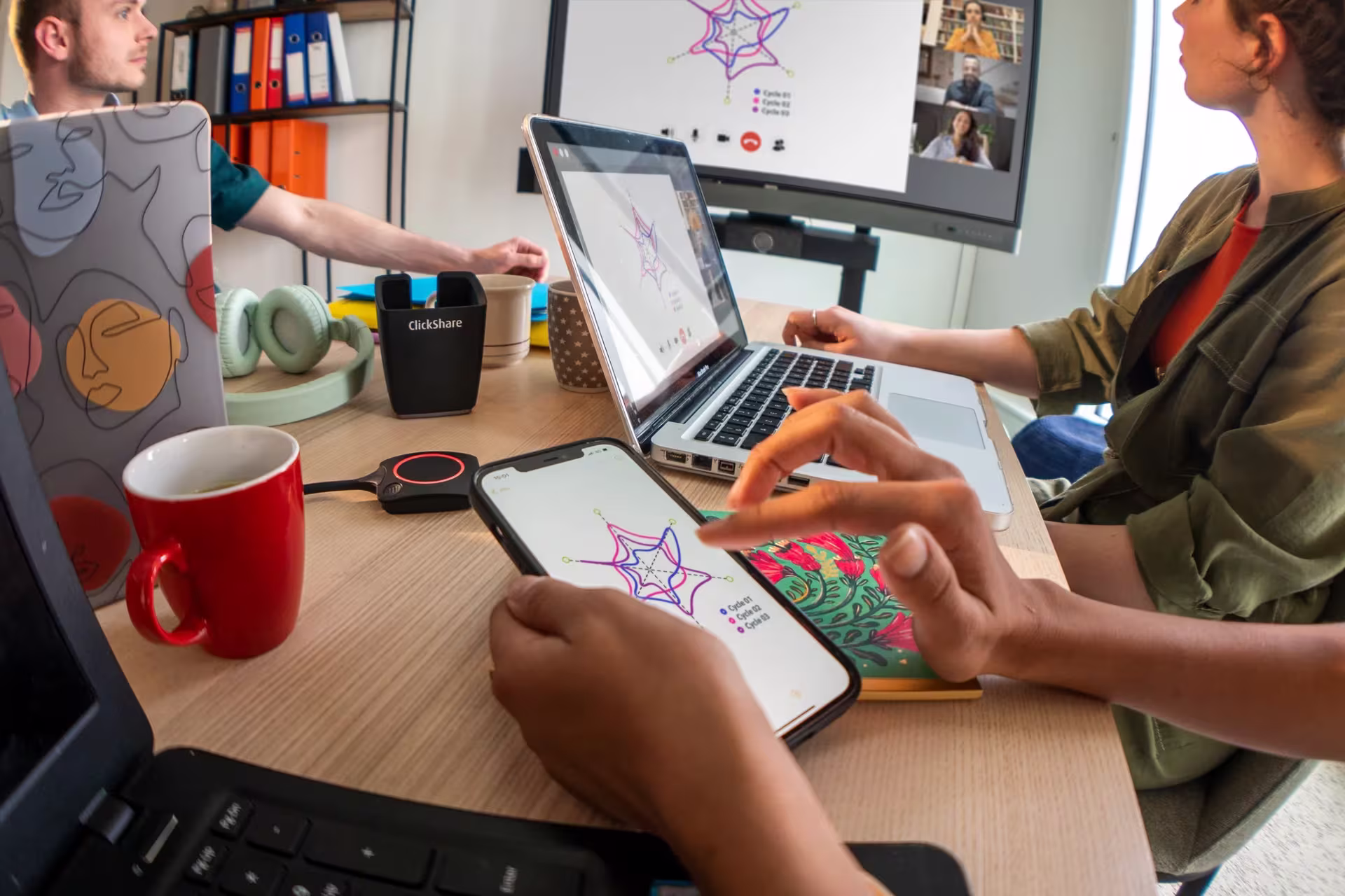 A meeting room with a laptop on the table and a display on the wall